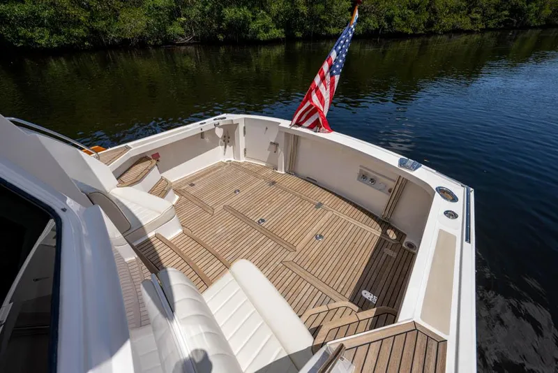 Slide: The Image of The image shows the aft deck of a 2007 Grand Banks 43 Eastbay SX with teak flooring and a US flag. - 1