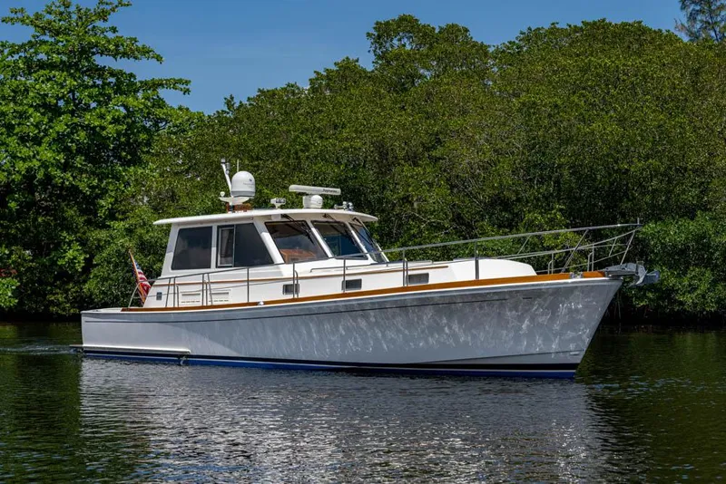 Slide: The Image of 2007 Grand Banks 43 Eastbay SX on calm water with a lush green backdrop. - 11