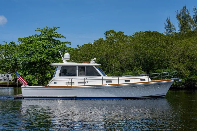 Slide: The Image of 2007 Grand Banks 43 Eastbay SX yacht on calm water, surrounded by lush greenery. - 55