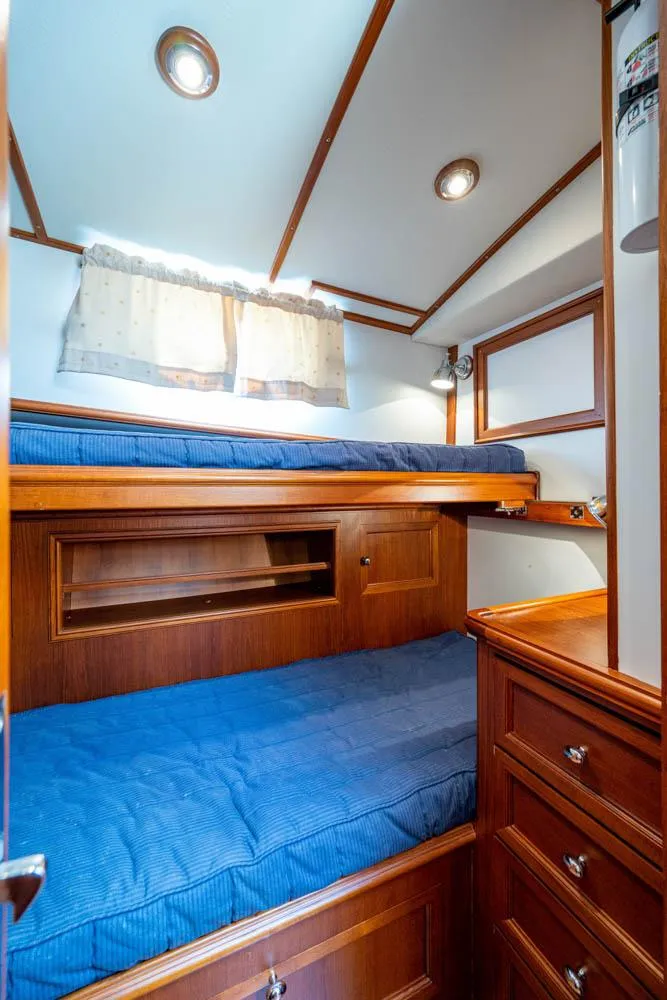 Slide: The Image of Cabin with two blue bunk beds, wooden furniture, and a small window. - 42