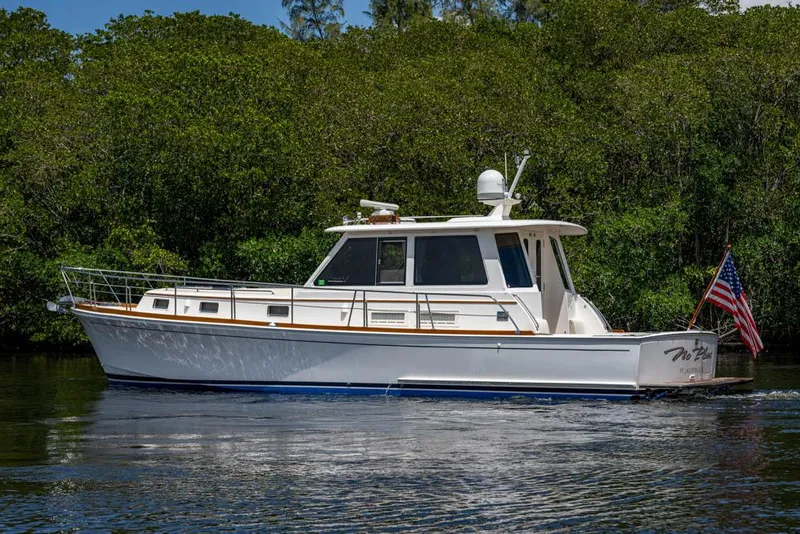 Slide: The Image of 2007 Grand Banks 43 Eastbay SX on calm water, surrounded by lush greenery. - 48