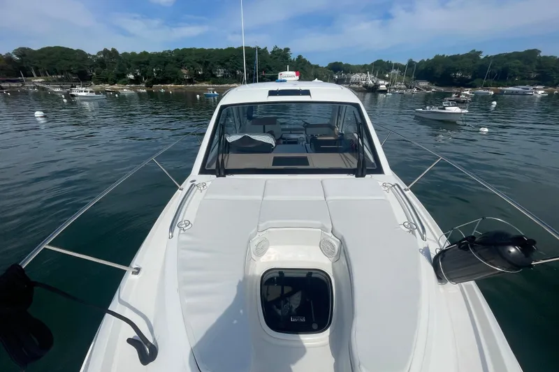 Slide: The Image of 2018 Sea Ray Sundancer 350 Coupe on calm water, surrounded by boats and lush greenery. - 33