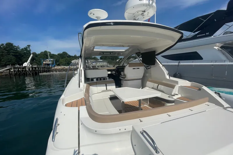Slide: The Image of 2018 Sea Ray Sundancer 350 Coupe yacht with spacious seating and table, docked by the water. - 4