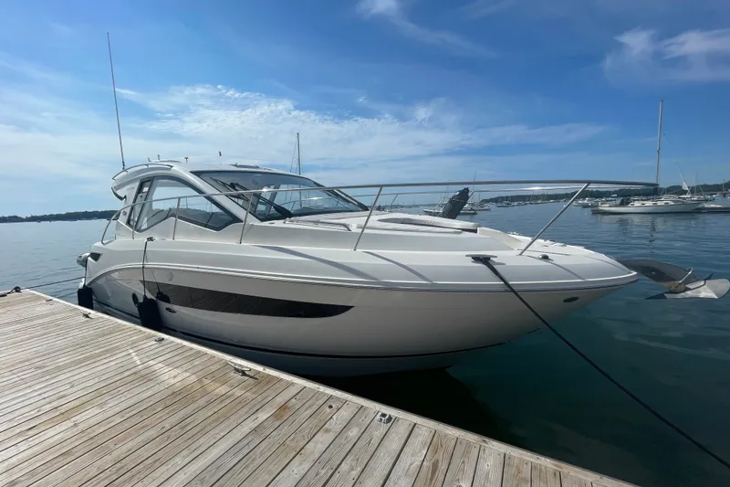 Slide: The Image of 2018 Sea Ray Sundancer 350 Coupe docked at a marina under a clear blue sky. - 1