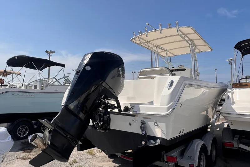 Slide: The Image of 2022 Sailfish 242 CC boat with outboard motor, parked on a trailer under clear skies. - 5