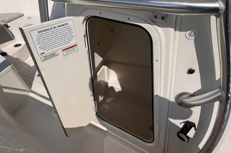 Slide: The Image of Open storage compartment on 2022 Sailfish 242 CC boat, featuring safety warning label. - 13