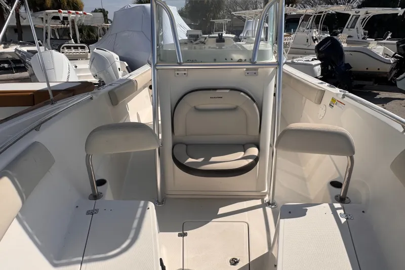 Slide: The Image of 2022 Sailfish 242 CC boat interior with seating and console, docked among other boats. - 10