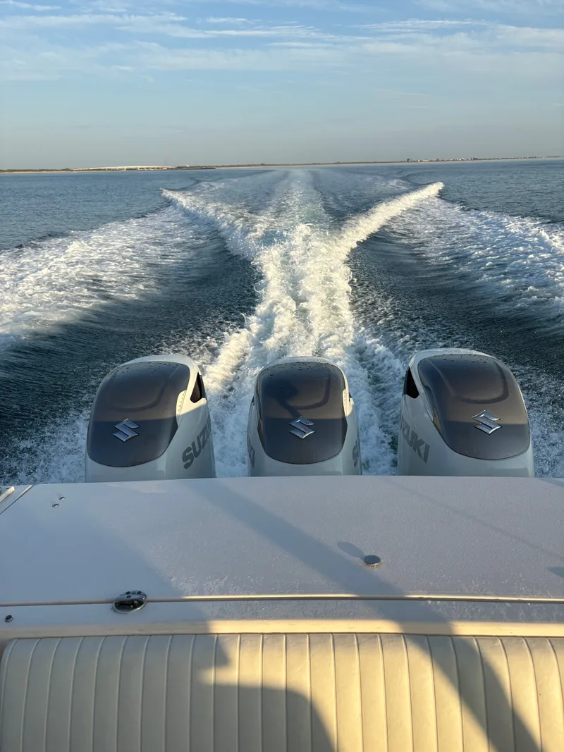 Slide: The Image of Three Suzuki outboard engines power a boat cruising on calm water, leaving a wake behind. - 22