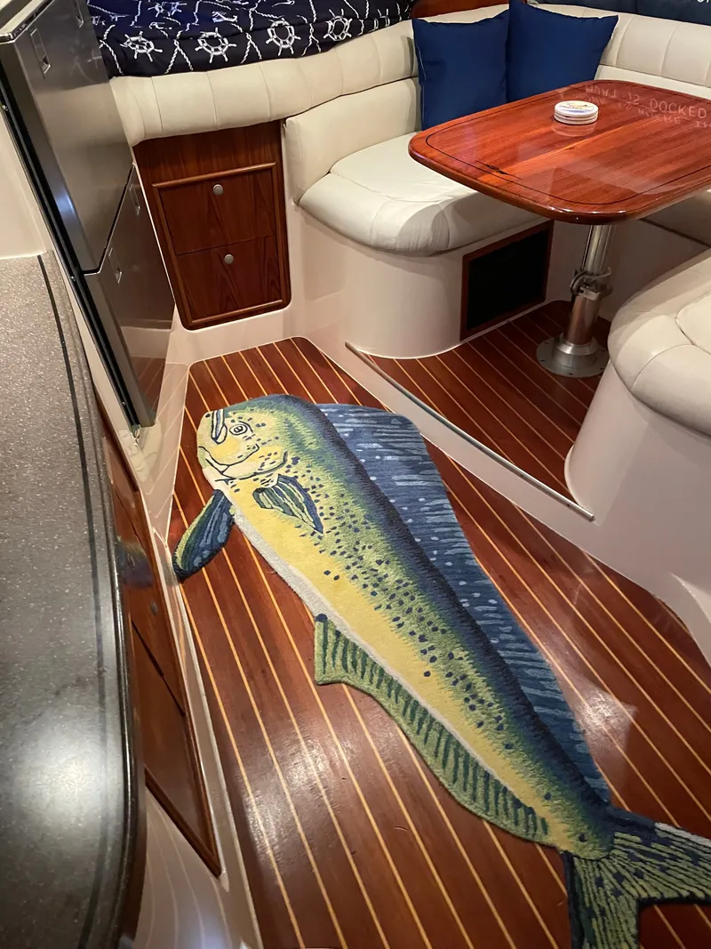 Slide: The Image of Interior of a 2005 Grady-White Express 360 with wood flooring and a fish-themed rug. - 10