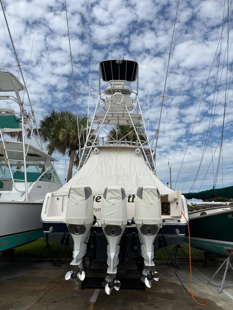 Slide: The Image of A 2005 Grady-White Express 360 boat with four outboard engines, on dry dock under a cloudy sky. - 34