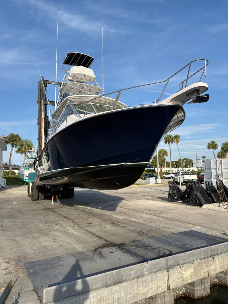 Slide: The Image of A 2005 Grady-White Express 360 boat being lifted out of the water. It has a dark blue hull and spacious cabin. - 29