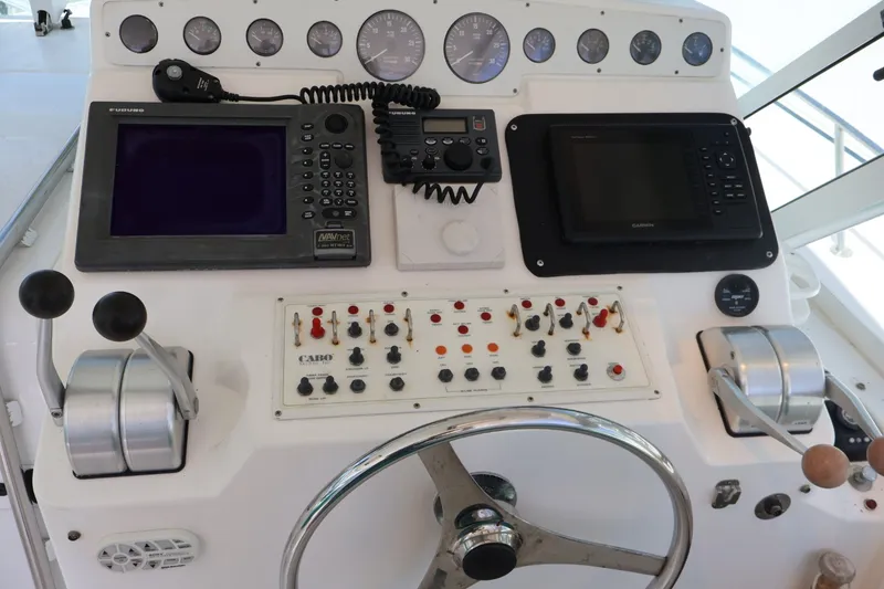 Slide: The Image of The image shows the helm of a 2001 Cabo 35 Express with various instruments and control levers. - 10