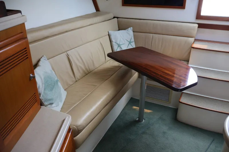 Slide: The Image of Interior of the 2001 Cabo 35 Express with beige sofa and wooden table. - 13