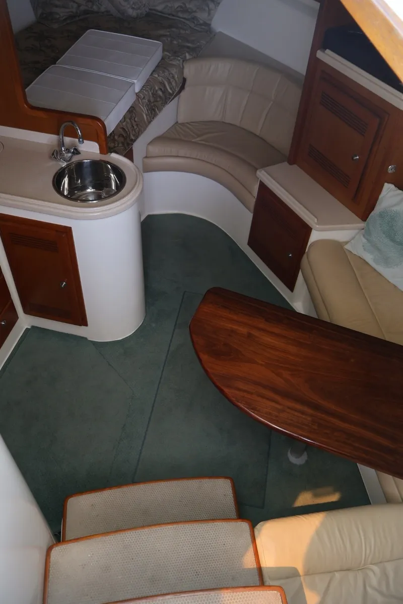 Slide: The Image of Interior of the 2001 Cabo 35 Express with seating area, wooden table, and small kitchenette. - 12