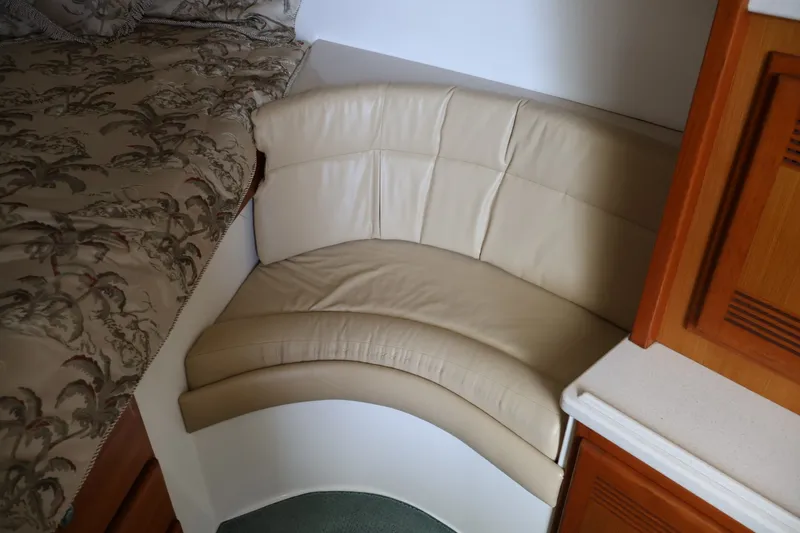 Slide: The Image of Corner with beige leather seat next to a bed and wooden cabinetry in a boat cabin. - 16