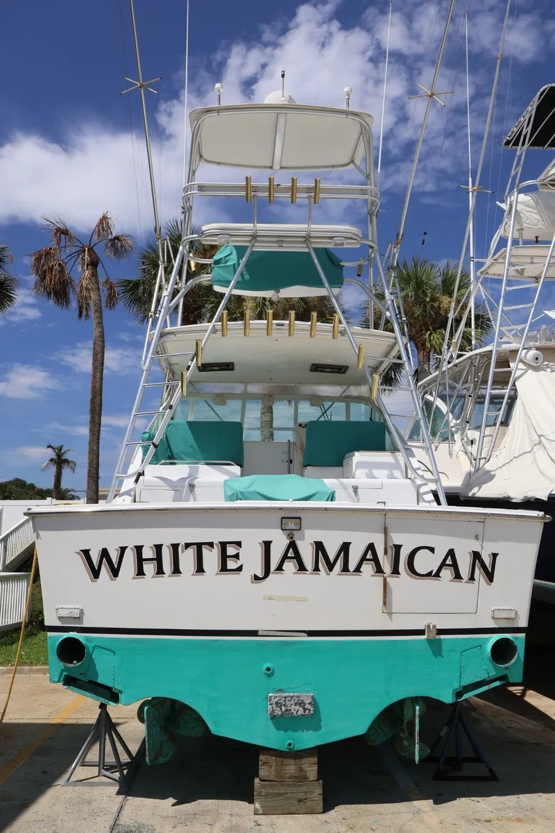 Slide: The Image of The image shows a 2001 Cabo 35 Express boat named "White Jamaican." It has a turquoise bottom and is parked on land. - 3
