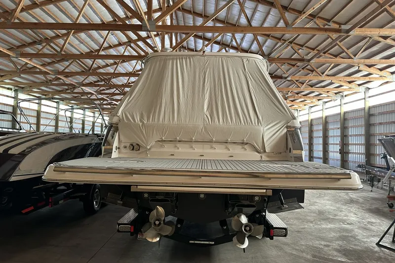 Slide: The Image of 2023 Regal LS36 boat in storage, covered, with visible propellers and wooden ceiling beams. - 2