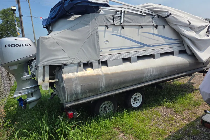 Slide: The Image of 2007 Quest mini pontoon boat with Honda motor on trailer, covered and parked on grass. - 3