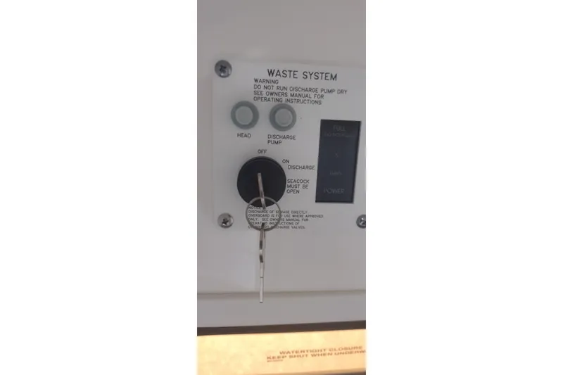 Slide: The Image of Control panel of 2023 Sea Ray SDX 270 waste system with key and instructions. - 52