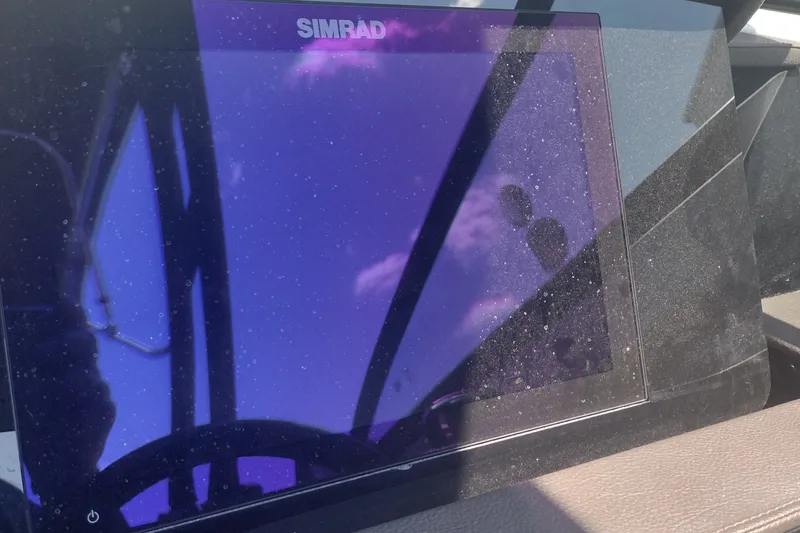 Slide: The Image of Simrad display on 2023 Sea Ray SDX 270 boat dashboard, reflecting sky and clouds. - 25