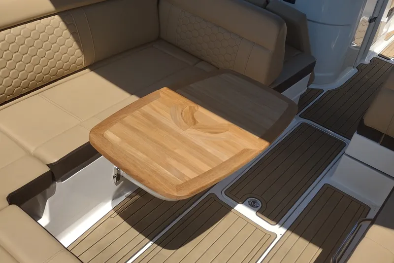 Slide: The Image of 2023 Sea Ray SDX 270 boat interior with beige seating and wooden table. - 46