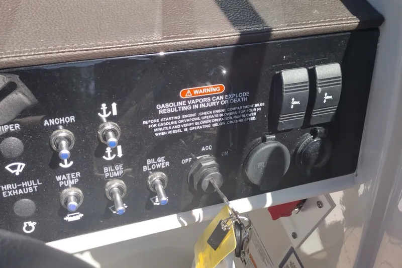 Slide: The Image of Control panel of a 2023 Sea Ray SDX 270 boat with various switches and warning label. - 27