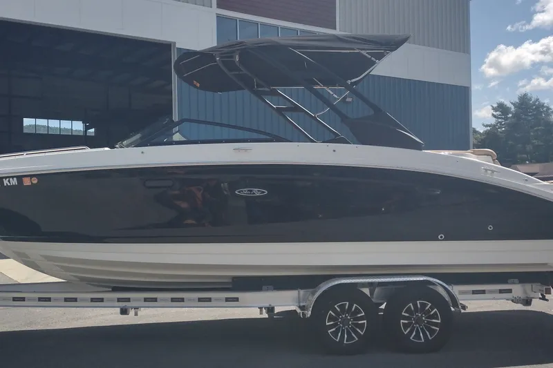 The Image of 2023 Sea Ray SDX 270 boat on trailer, parked outside a large building. - 1