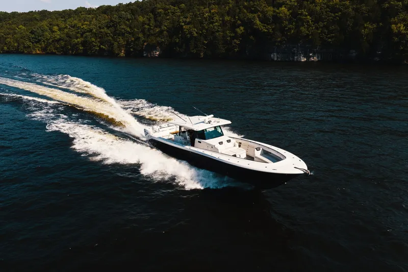 Slide: The Image of 2018 HCB 53 Suenos boat cruising on a scenic lake with forested shoreline. - 53