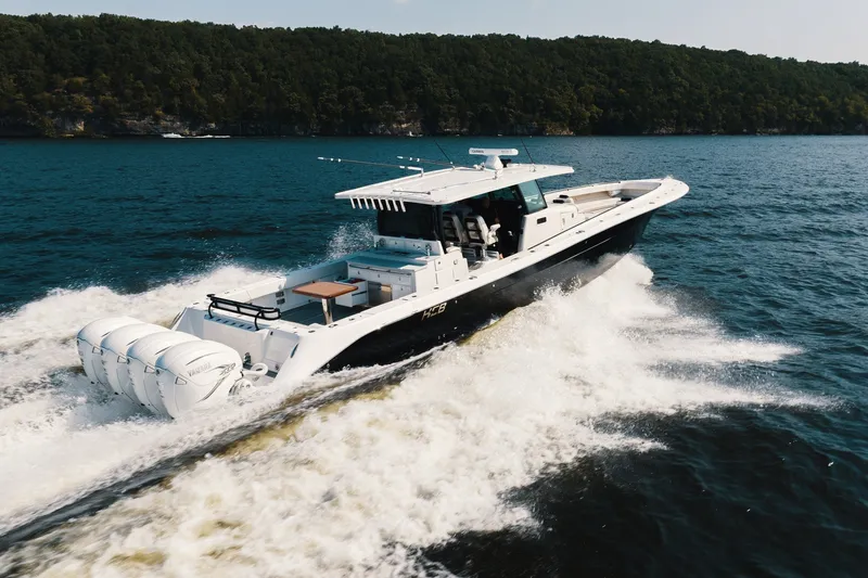 Slide: The Image of 2018 HCB 53 Suenos boat cruising on open water, surrounded by lush greenery. - 58