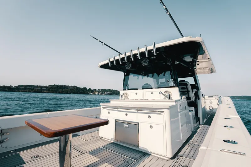 Slide: The Image of 2018 HCB 53 Suenos boat with fishing rods, sleek deck, and ocean backdrop. - 19