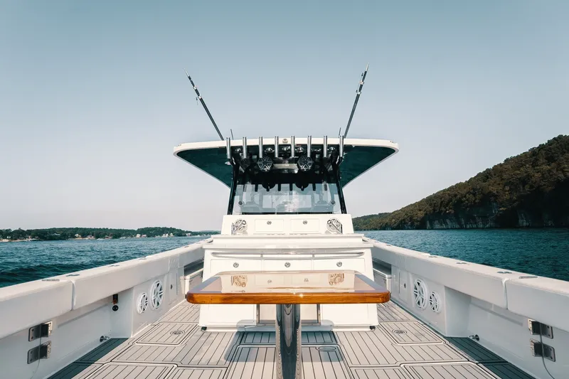Slide: The Image of 2018 HCB 53 Suenos boat on open water, featuring sleek deck design and fishing rods. - 18