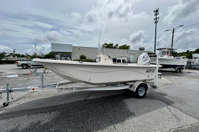 The Image of 2025 Carolina Skiff 19 LS boat on trailer in parking lot, overcast sky. - 0