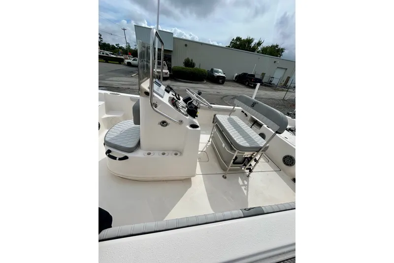 Slide: The Image of 2025 Carolina Skiff 19 LS boat interior with seating and console, parked outdoors. - 11