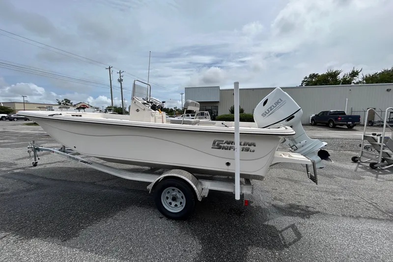 Slide: The Image of 2025 Carolina Skiff 19 LS boat on trailer, parked outdoors with Suzuki outboard motor. - 4