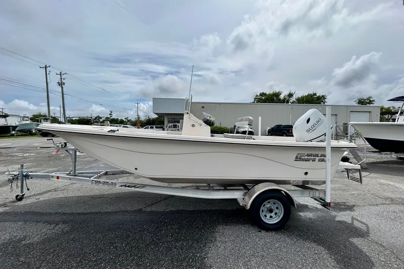 Slide: The Image of 2025 Carolina Skiff 19 LS boat on trailer, parked outdoors under cloudy sky. - 1