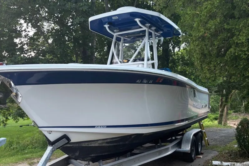 Slide: The Image of 2019 Blackfin 242 CC boat on trailer, surrounded by trees. - 2