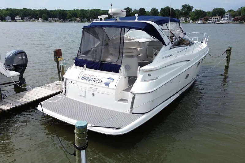 Slide: The Image of 2004 Regal Commodore 3860 yacht docked on a serene lake with lush greenery. - 5