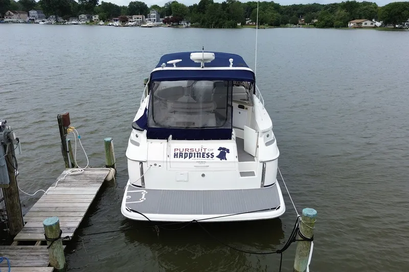 Slide: The Image of 2004 Regal Commodore 3860 yacht docked on a serene lake with lush greenery. - 2