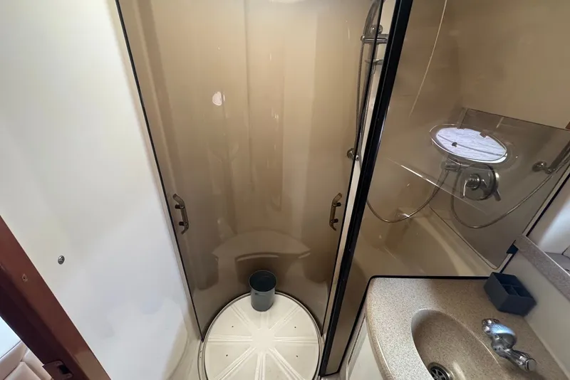 Slide: The Image of 2004 Regal Commodore 3860 yacht bathroom with shower, sink, and porthole window. - 21