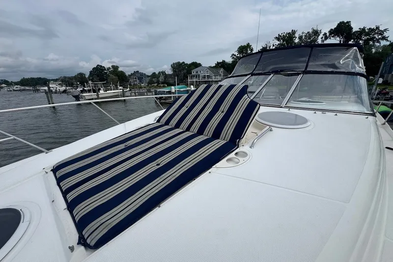 Slide: The Image of 2004 Regal Commodore 3860 yacht with striped sunbed on deck, docked by waterfront homes. - 7