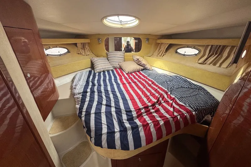 Slide: The Image of Cozy cabin interior of 2004 Regal Commodore 3860 with striped bedding and porthole windows. - 18