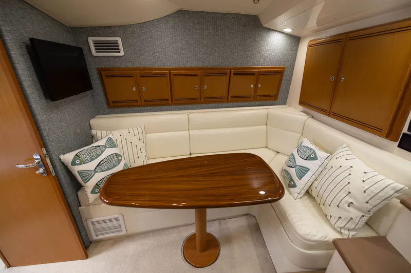 Slide: The Image of Luxurious 2007 Cabo 31 Express yacht interior with plush seating, wooden table, and decorative pillows. - 35