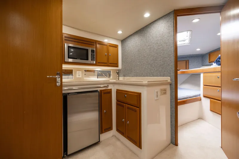Slide: The Image of 2007 Cabo 31 Express yacht interior with kitchenette, microwave, fridge, and cozy sleeping area. - 3
