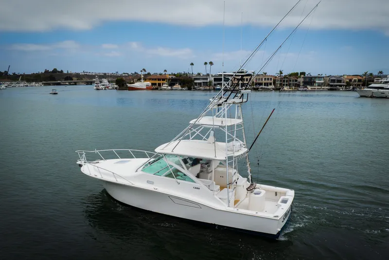 Slide: The Image of 2007 Cabo 31 Express boat cruising in a scenic marina with waterfront homes. - 46