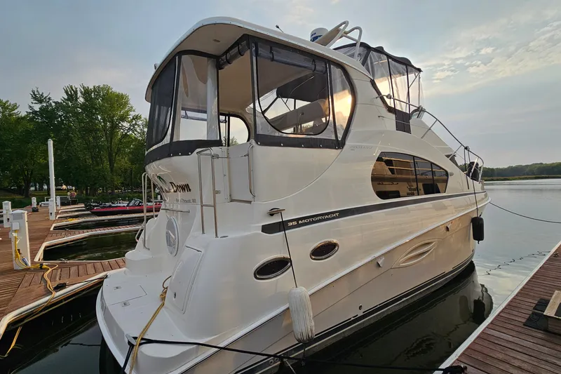 Slide: The Image of 2003 Silverton 35 Motor Yacht docked at a marina, surrounded by calm water and trees. - 3