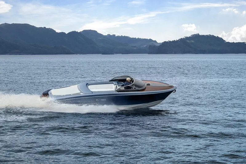 Slide: The Image of 2004 Riva El-Iseo speedboat cruising on a scenic lake with mountainous backdrop. - 0