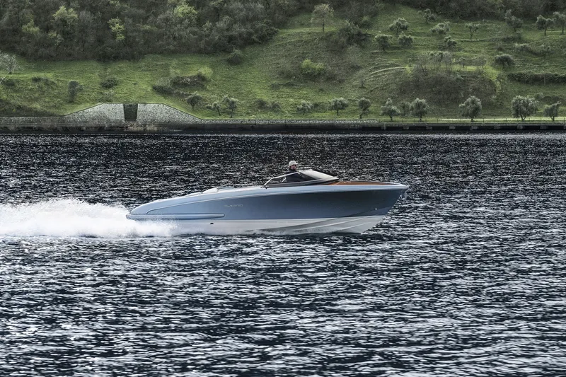 Slide: The Image of 2004 Riva El-Iseo speedboat cruising on a scenic lake with lush green hills. - 17