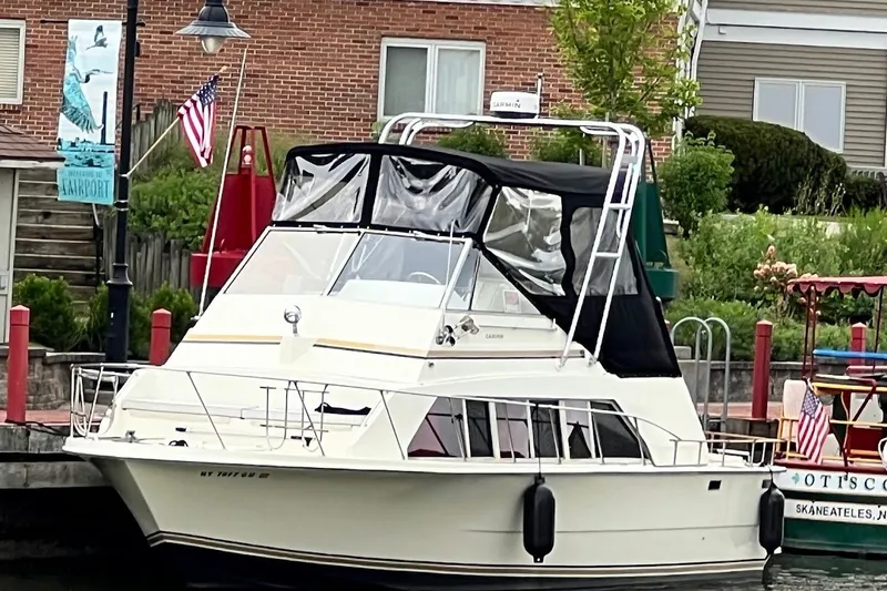 Slide: The Image of 1980 Carver 33 Mariner docked, featuring a black canopy and American flag. - 3