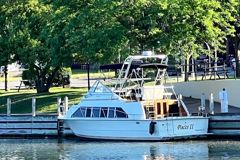 The Image of 1980 Carver 33 Mariner docked by a lush, tree-lined waterfront. - 1