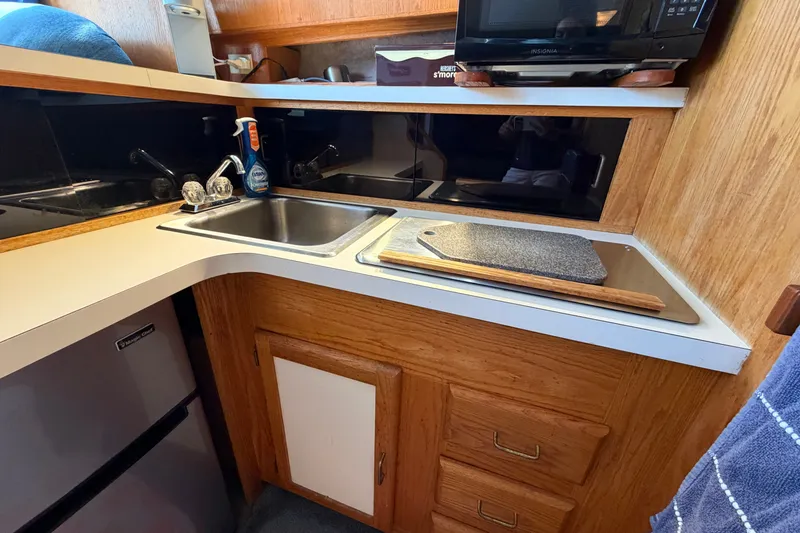 Slide: The Image of Compact kitchen area in a 1987 Silverton 34 Convertible boat with sink and appliances. - 27